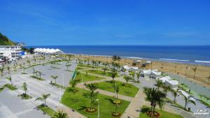 埃斯梅拉达斯Hotel Perla Verde的享有棕榈树和遮阳伞海滩的空中景致