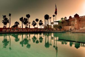 恩塞纳达港滨海别墅酒店的一座棕榈树大型游泳池和一座建筑