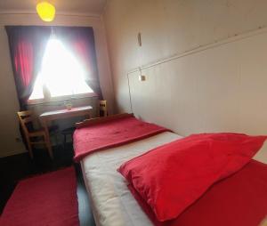 StorlienStorliens Fjällgård的一间卧室配有两张带红色床单的床和一张书桌