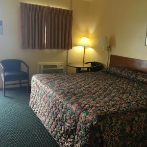 ChanuteGuest House Motel Chanute的酒店客房配有一张床铺和一张桌子。