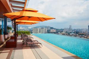 吉隆坡吉隆坡双威伟乐酒店的一座大楼内的游泳池,配有椅子和遮阳伞