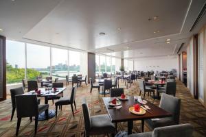 新泻新泻日航酒店的餐厅设有桌椅和大窗户。