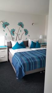 奥伊斯基兴多夫克鲁格旅馆的卧室配有蓝色和白色的床,墙上挂着蓝色的鲜花