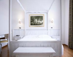 萨尼科赛比诺酒店的卧室配有一张白色床,墙上挂着一幅画