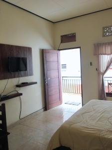 金巴兰德思德考斯特巴厘岛民宿的一间卧室配有一张床、一台电视和一扇门