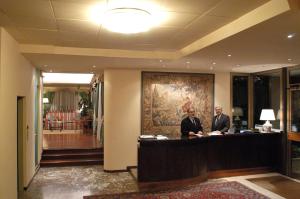 蒙特卡蒂尼泰尔梅托雷塔酒店的两名男子站在酒店大堂的桌子旁