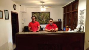 日惹布拉多克酒店&餐厅的两个穿着红衬衫的人站在柜台