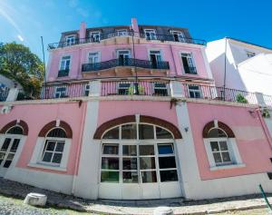 里斯本Safestay Lisbon Bairro Alto的一座粉红色的建筑,上面设有一个阳台