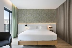 巴塞罗那纽巴塞罗那酒店的卧室配有一张白色大床和一把椅子
