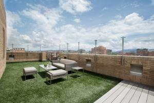 波哥大Attik Luxury Apts的屋顶庭院设有草地和桌椅