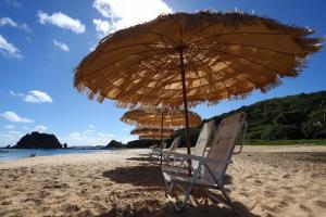 费尔南多 - 迪诺罗尼亚Casa Conceição的海滩上的两把椅子和一把遮阳伞