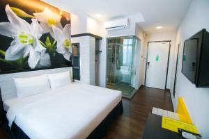 怡保因陀罗酒店 - 精品套房的卧室配有一张床,墙上挂着鲜花
