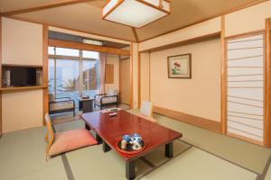 西伊豆町堂岛温泉日式旅馆的一间带桌子的客厅和一间餐厅