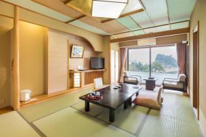 西伊豆町堂岛温泉日式旅馆的客厅设有咖啡桌和大窗户