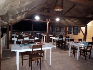 KpaliméHotel Chez Fanny的用餐室配有白色的桌子和木椅