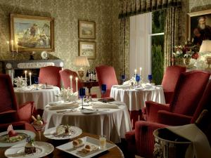 威廉堡英威尔洛奇城堡酒店的一间设有两张桌子和红色椅子的用餐室