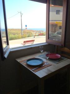 科武港Casa de Mar @ Porto Côvo的窗户上带酒盘和酒杯的桌子