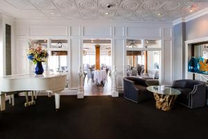 Port Jefferson Station丹福德斯酒店及码头的一间设有白色钢琴和桌子的用餐室