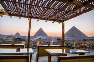 开罗卫报旅馆的餐厅设有桌子,享有金字塔的景色