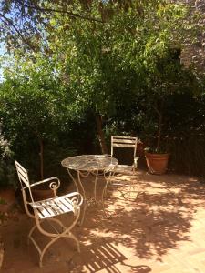 森普罗尼亚诺Le Antiche Mura的庭院配有桌子和两把椅子,树木繁茂。