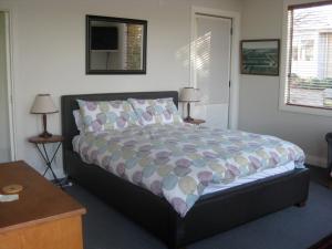 布伦海姆Korohi Vineyard BnB的一间卧室配有一张床、两张桌子和两盏灯。
