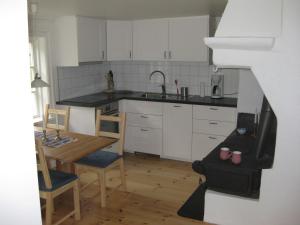 Östra LöaHyttsnåret的厨房配有白色橱柜、桌子和水槽。