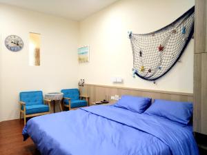 台南基石民宿 的一间卧室配有一张床和两张蓝色椅子