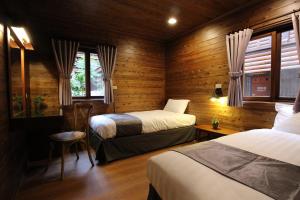 和平区台中商务旅馆－八仙山庄 的配有木墙和窗户的客房内的两张床