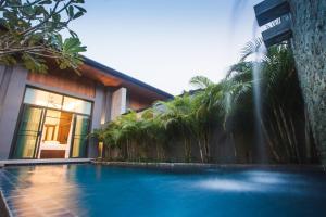 奈汉海滩Two Villas HOLIDAY - Onyx Style Nai Harn Beach, Phuket的一座带喷泉的建筑前的游泳池