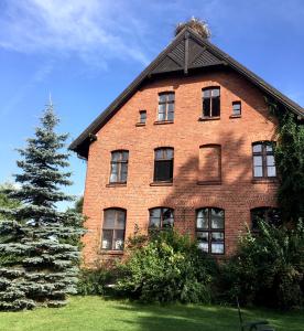 PozezdrzeStara Szkoła w Harszu的前面有一棵树的大型砖砌建筑