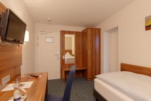 圣英贝特alfa hotel的酒店客房配有一张床、一张书桌和一台电视。