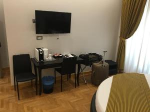 罗马罗马威尼托旅馆的酒店客房设有一张桌子和一台墙上的电视