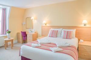 伊斯特布恩皇后酒店的一间卧室配有一张大床和毛巾