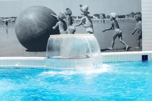 贝诺代Hotel Kastel & Spa avec piscine d'eau de mer chauffée的一群儿童在带大球的游泳池玩耍