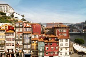 波尔图Oca Ribeira do Porto Hotel的一组建筑,有一座桥在后面