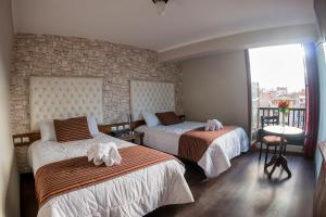 库斯科Ureta Hotel的酒店客房设有两张床和窗户。