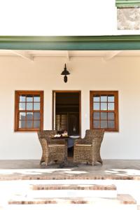 帕尔d'Olyfboom Guest House B & B的庭院配有2把藤椅和桌子