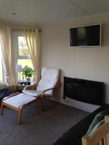 亨伯河畔巴顿Marshlands Lakeside Nature Retreat的客厅配有椅子和平面电视