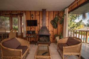 阿尔加罗沃Pao Pao Lodge Algarrobo的客厅设有壁炉、椅子和电视