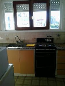 马德普拉塔Panoramico Playa Grande -Solo Familias的厨房配有炉灶、水槽和窗户。