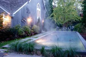 东汉普顿米尔之家住宿加早餐旅馆的一座带灯光的房屋的庭院内的游泳池
