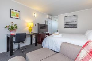 奥克兰安扎克庭院汽车旅馆的酒店客房配有一张床、一张书桌和一张沙发。