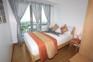 马尼拉茂伊蔚蓝公寓式酒店的一间卧室设有一张床和一个大窗户