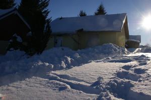伦斯泰格地区施米德费尔德Ferienhaus Feldmann的雪覆盖的房子,后面有太阳