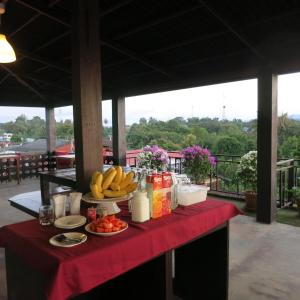 Ban Khun Yuam永特酒店的一张桌子,上面有水果和饮料,放在红色桌布上