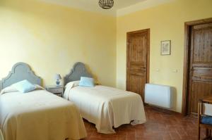 巴斯基里奥Agriturismo Borgo San Francesco的黄色墙壁客房的两张床