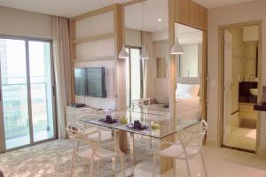纳塔尔Premium Flat Ponta Negra Natal的一间设有玻璃桌、椅子和一张床的房间