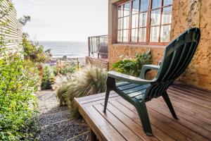 阿尔加罗沃Cinque Colori Bed & Breakfast- Spa的一张绿色椅子,坐在木甲板上,眺望着大海