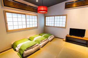 大阪Bijou Suites Nagomi的客房配有带绿色枕头的床和电视。