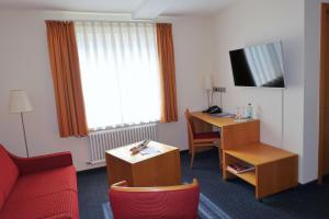 埃尔万根塔格恩豪斯舍嫩贝格酒店的酒店客房配有红色的沙发、书桌和电视。